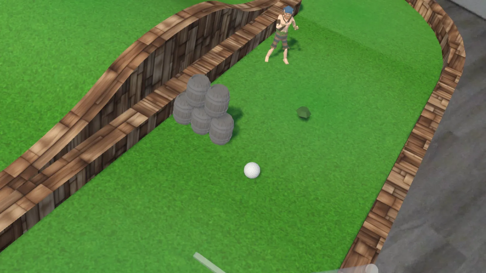Puttscape gameplay from the player’s view: a white ball on a green course with wooden rails, a stack of barrels, a character standing at the far end, and the putter in the foreground.